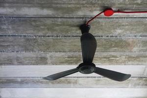 ventilador de hierro colgado en el techo de hormigón con cables rojos. foto