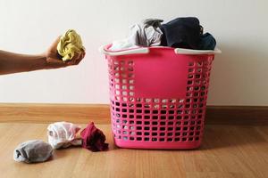 Basket with dirty laundry on the wooden floor in room and a man's hand holding a dirty cloth. photo