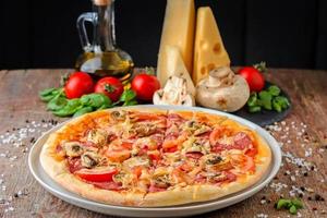 Pizza with ingredients on a wooden background, close up photo