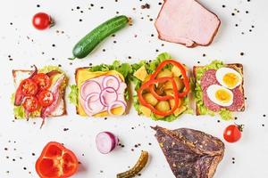 Different kind of sandwich and ingredients on a white background, top view photo