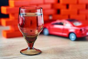 Drunk driving car crash accident. Don't drive after drink concept. Shot glass and a broken car photo