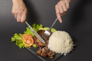 grilled beef with rice on plate over black background studio photo
