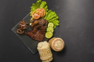 grilled beef with sticky rice on plate over black background studio photo