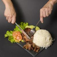 Carne de res a la parrilla con arroz en un plato sobre un estudio de fondo negro foto