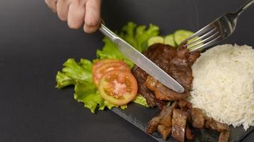 grilled beef with rice on plate over black background studio photo