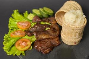 grilled beef with sticky rice on plate over black background studio photo