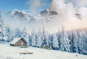 Cabin in the mountains in winter. Mysterious fog. photo