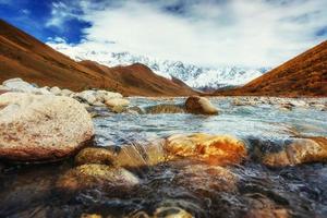 Snowy mountains and noisy mountain river. photo