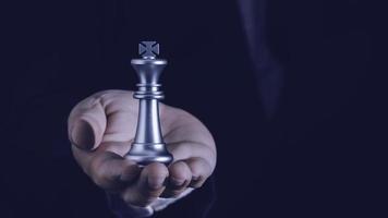mano del hombre de negocios que sostiene el ajedrez rey de plata para luchar para jugar con éxito en la competencia con el concepto de ideas de estrategia, liderazgo y gestión. foto
