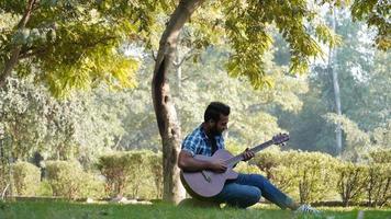 young boy with his guitar and playing guitar in park photo