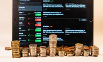 Coins are arranged differently in front of the tablet,Investment is risky, Business and finance concept. photo
