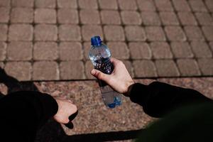 athletic man in hold bottle of water outdoors photo