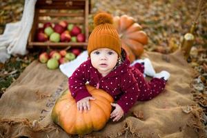 Little girl leans on a pumpkin. photo