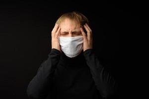 Middle aged man with medical face mask portrait close up illustrates pandemic coronavirus disease on dark background. Covid-19 outbreak contamination concept. photo