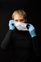 Protection against contagious disease, coronavirus. Man wearing hygienic mask to prevent infection 2019-nCoV. man's panic man puts on protective gloves photo