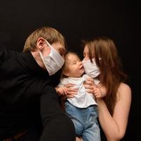 Masked parents take selfies with their little daughter. photo