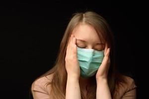 The girl in the medical mask shows the symptoms of the disease. photo