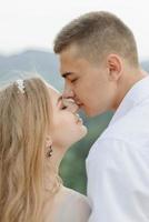 Photoshoot of a couple in love in the mountains. The girl is dressed like a bride in a wedding dress. photo