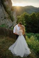 Photoshoot of a couple in love in the mountains. The girl is dressed like a bride in a wedding dress. photo