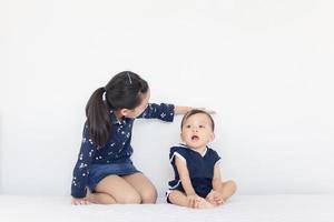 Sister measures the growth of her brother, kids playing on the bed, happy family concept photo
