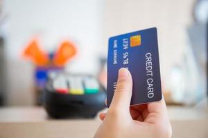 Hand of customer with credit card blurred credit card reader machine at bar counter, payment concept photo