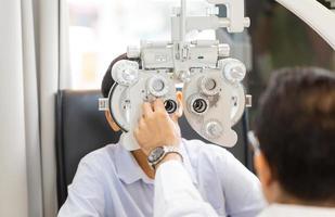 optometrista haciendo pruebas visuales para pacientes infantiles en la clínica, niño haciendo pruebas oculares con un optometrista en una tienda óptica