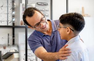 Indian father and son choosing eyeglasses in optics store photo