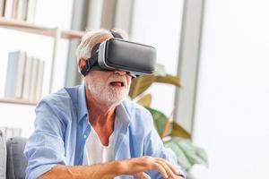 Senior man sitting on the sofa having fun with virtual reality glasses, Happy elderly technology concepts photo