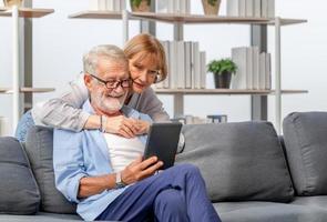 Portrait of Cheerful senior couple in living room, Elderly woman and a man using smartphone talking on video call on cozy sofa at home, Happy family concepts photo