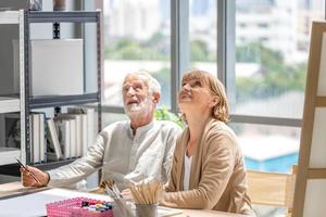 Older man and woman drawing together on a canvas at art studio, Portrait of Senior couple painting on a canvas in living room, Happy retirement concepts photo