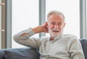 retrato de un anciano sonriente relajándose y disfrutando en la sala de estar foto