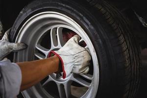 Close up of repair mechanic hands during maintenance and changing the tire of a car photo