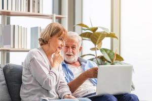 Portrait of happy senior couple in living room, Elderly woman and a man using computer laptop on cozy sofa at home, Happy family concepts photo