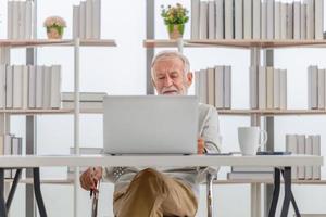 Portrait of Senior man using laptop and smartphone at home, Mature man in living room with laptop browsing internet on modern computer gadget photo