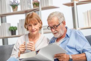 Relaxing senior couple in living room, Mature woman and a man reading a book on cozy sofa at home, Happy family concepts photo