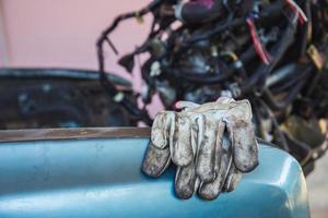 Leather gloves on car body chassis frame with blurred car engine background photo
