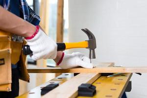 artesano usando un martillo clavado en el taller, carpintero usando el martillo golpeó un clavo para ensamblar madera en un taller de carpintería