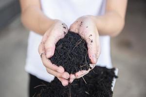 Little kid girl holding soil in hands with blurred background. growth concepts photo