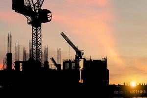 silueta del equipo de trabajadores en el sitio de construcción, sitio de construcción al atardecer en el tiempo de la tarde foto