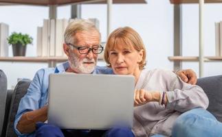 Mature woman and senior man using laptop in living room, Portrait of Worried senior couple checking their bills and work on netbook read document information at home photo