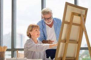 retrato de una pareja mayor feliz pintando en un lienzo en la sala de estar, un hombre mayor y una mujer dibujando juntos en un lienzo, conceptos de jubilación feliz foto