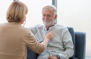 Selective focus of Female professional doctor hand hold stethoscope exam senior adult man patient, Elderly medical health care concepts photo