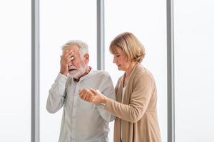 Depressed senior man. Elderly man suffering from headache and takes care by his wife photo
