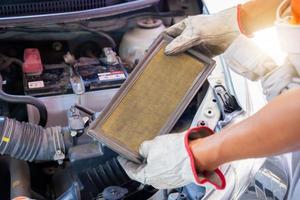 Auto mechanics holding air filter of car in the engine room, technician doing the checklist for repair car engine in the garage photo