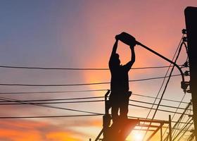 Silhouette of Electrician checking lighting to the LED street lamp post, Technician and maintenance service concepts photo