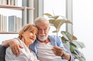 feliz pareja mayor en la sala de estar, anciano y una mujer relajándose en un acogedor sofá en casa, conceptos familiares felices foto