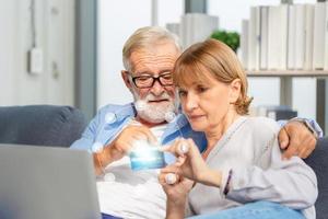 Senior couple shopping online in living room, Elderly man and woman using computer laptop on cozy sofa at home, Happy family concepts photo
