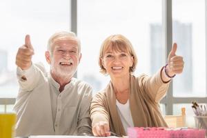 feliz pareja de ancianos en el taller en el estudio de arte, sonriente pareja de ancianos mostrando los pulgares hacia arriba foto