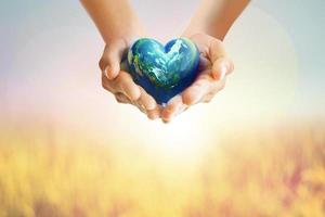 Human Hands holding Earth ball in heart shape on pastel background for World Health Day content and copy space.Elements of this image furnished by NASA photo