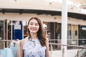 mujer adulta joven asiática en el centro comercial al aire libre con bolsas de compras. foto